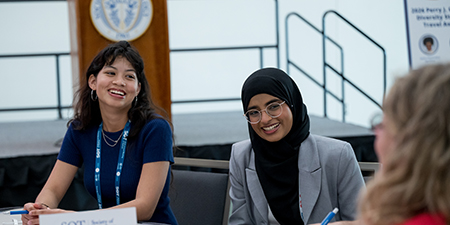 Two SOT Annual Meeting attendees smile during a small group discussion at a table. ” 