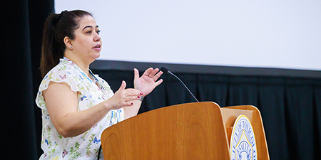 A presenter speaks from a podium during a session. 