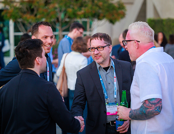 Four SOT Annual Meeting attendees converse and shake hands. 