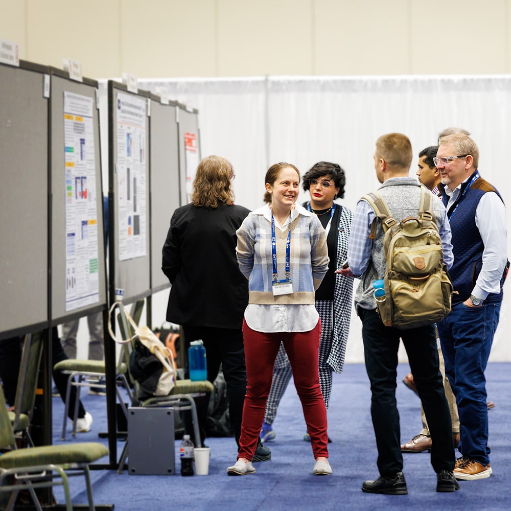 Individuals are clustered in discussion groups in front of poster displays.