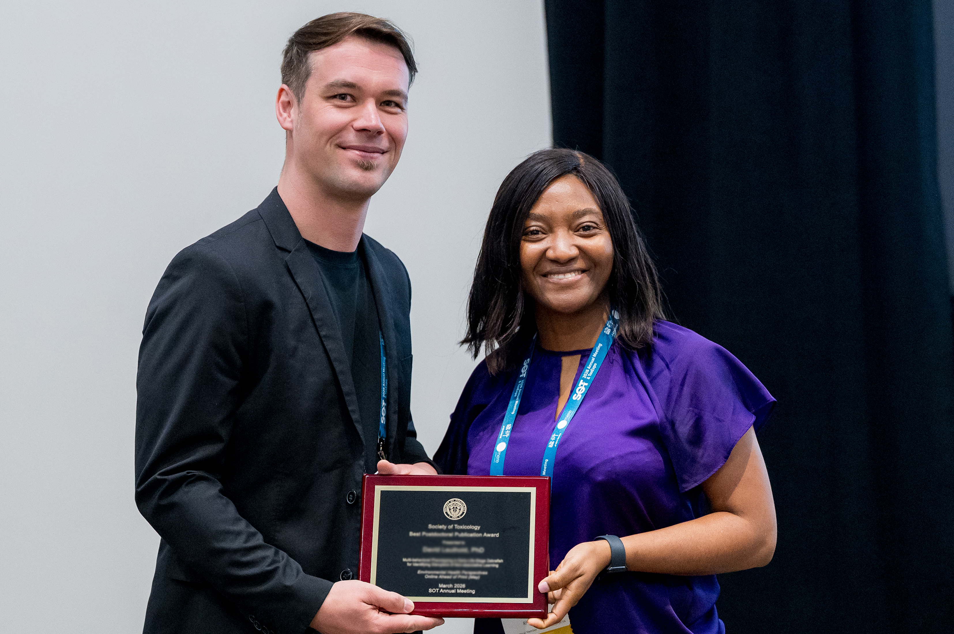 Two SOT Annual Meeting attendees stand together holding an award plaque. 