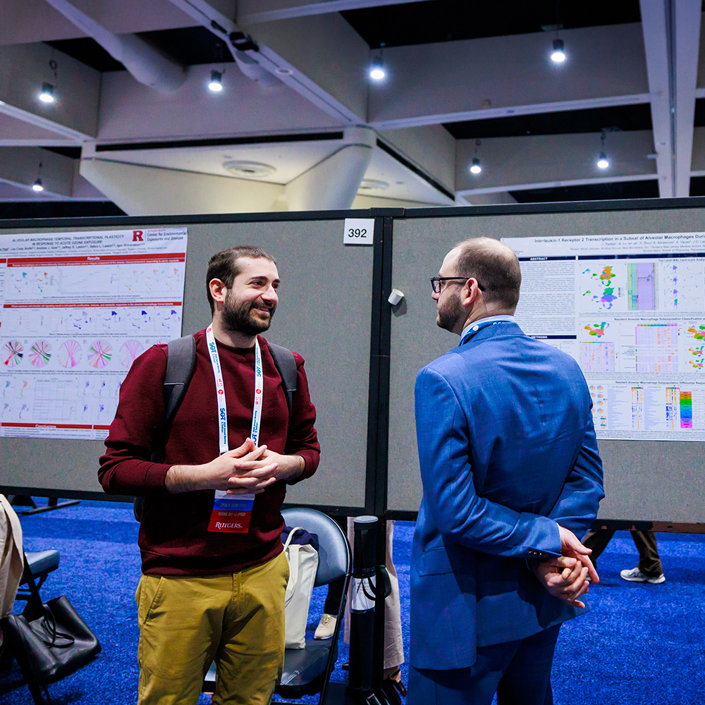 A pair of individuals stand between two poster displays. They are chatting.