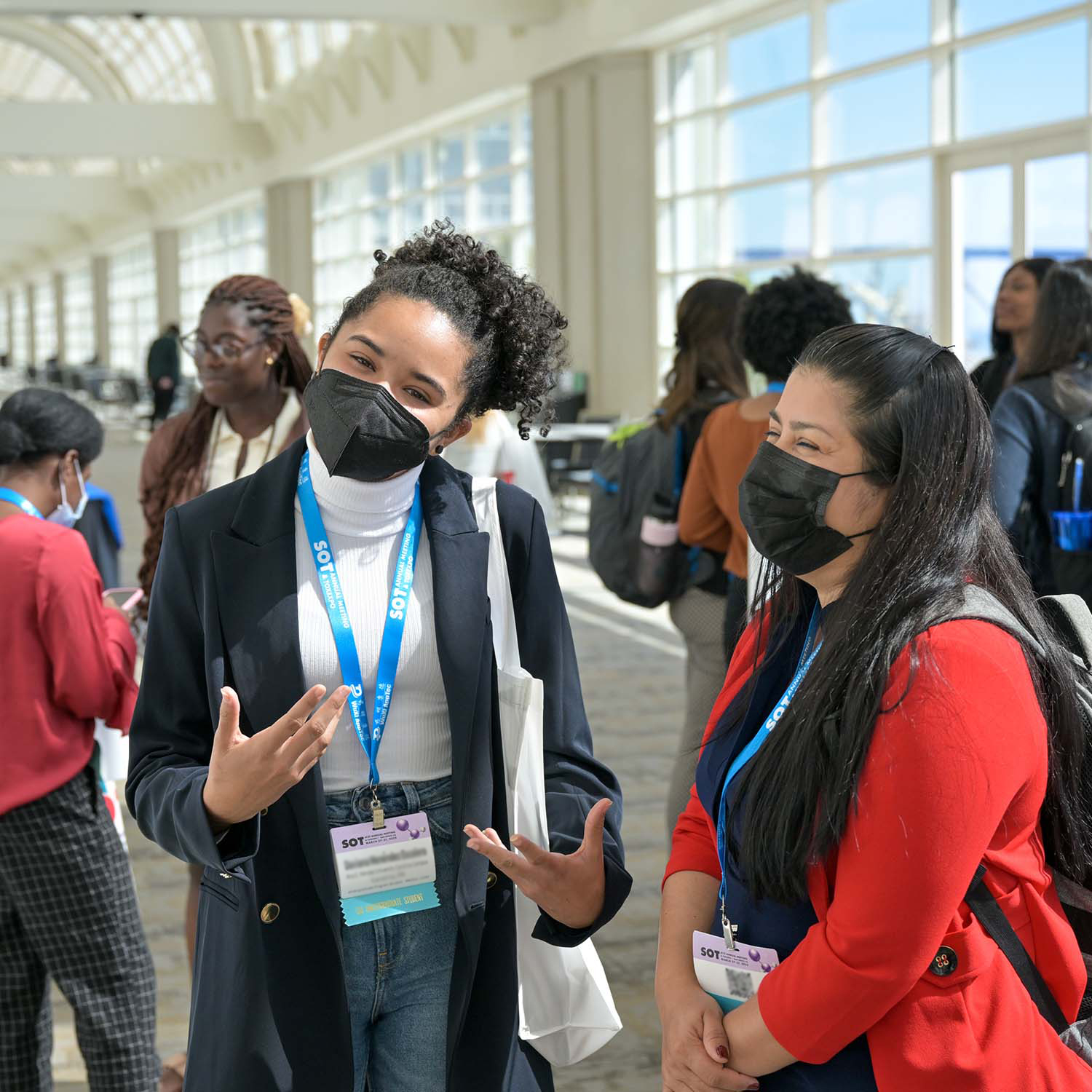 A young woman sits across from a man whose back is to the camera. The woman is speaking and gesturing.