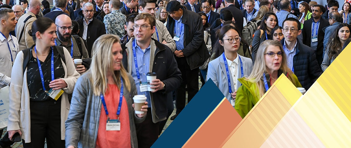A wide hallway in a convention center contains a sea of people.