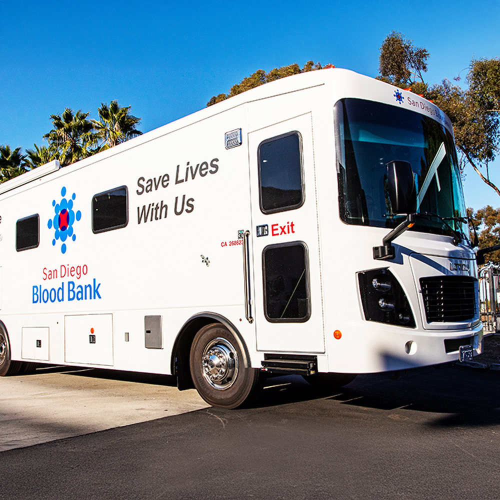 A large, white bus with the words Save Lives with Us on it.