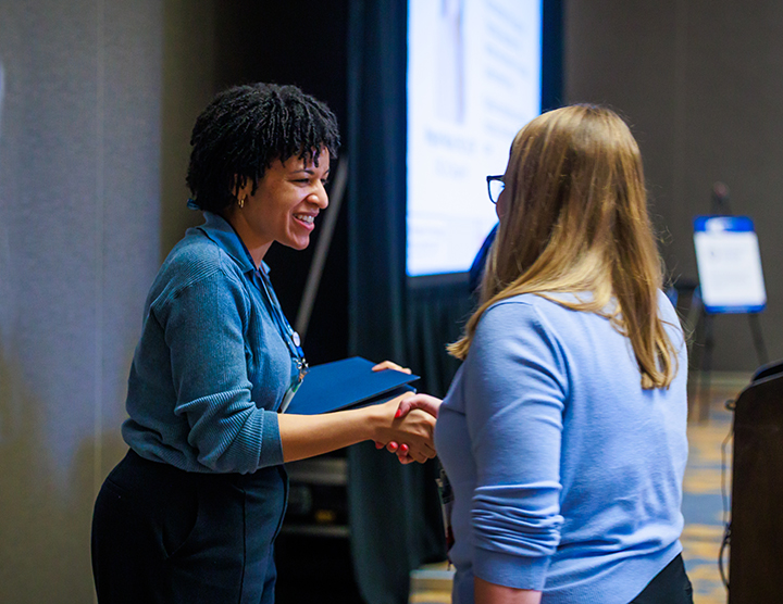 Two SOT Annual Meeting attendees shake hands. 