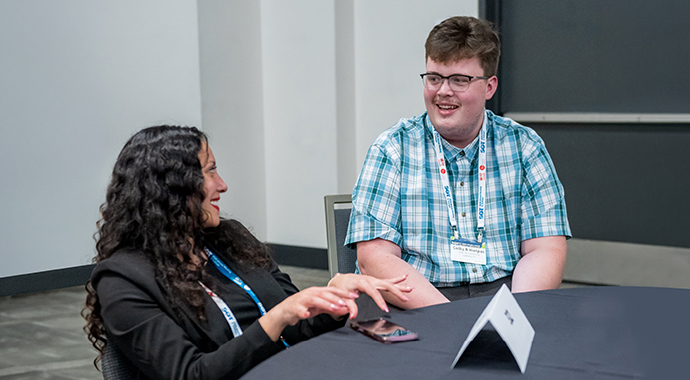 Two SOT Annual Meeting attendees sit at a table and talk. 