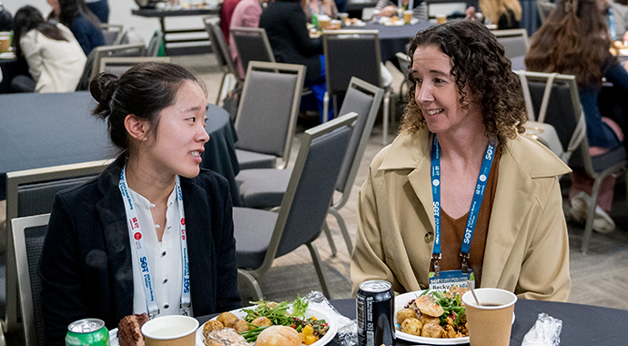 Two SOT Annual Meeting attendees talk over lunch at a table. 