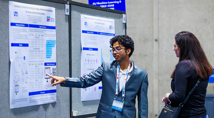 An SOT Annual Meeting attendee presents a poster to another attendee. 