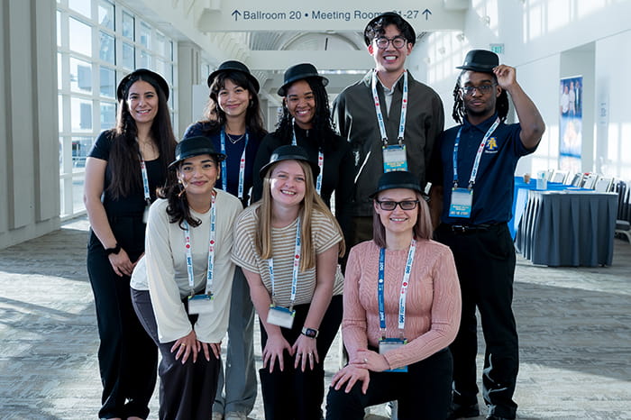 A group of SOT Annual Meeting attendees pose together in a bright hallway. 