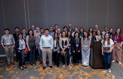 A large group of SOT Annual Meeting attendees pose together for a group photo in a conference room.